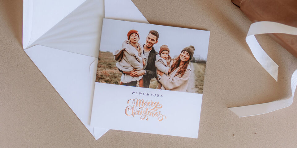 Familie in warmen Kleidern wünscht frohe Weihnachten mit einem fröhlichen Gruß auf einer Karte