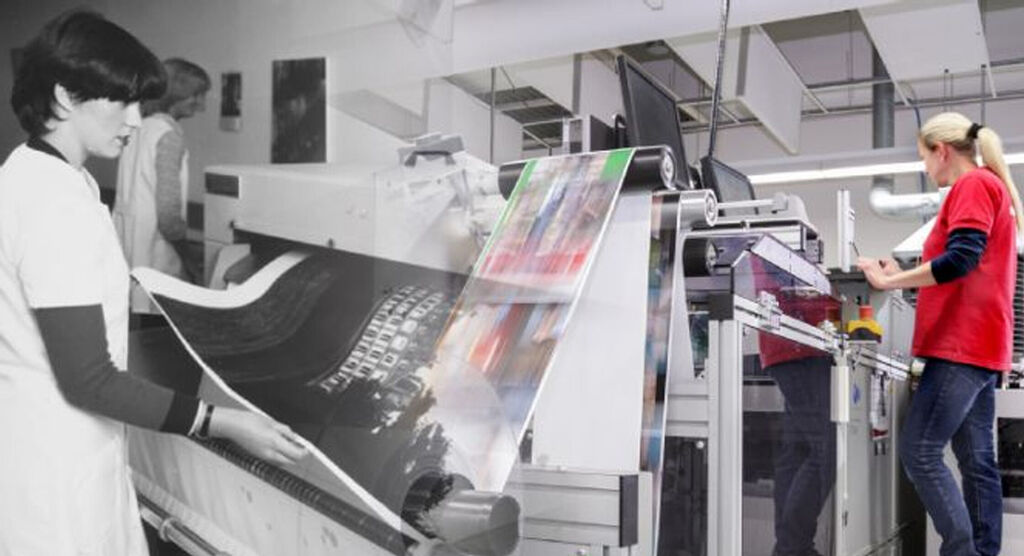 Zwei Frauen arbeiteten in einer Druckerei, die Druckmaschine zeigt verschiedene Druckerzeugnisse