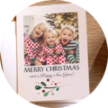 Zwei Kinder in festlichen Weihnachtsanzügen lachen vor einem geschmückten Baum