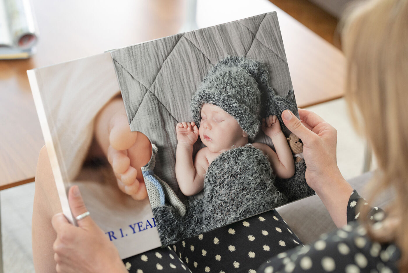 Eine Person hält ein liebevoll gestaltetes CEWE FOTOBUCH mit einem Babyfoto und einer weichen Babydecke.