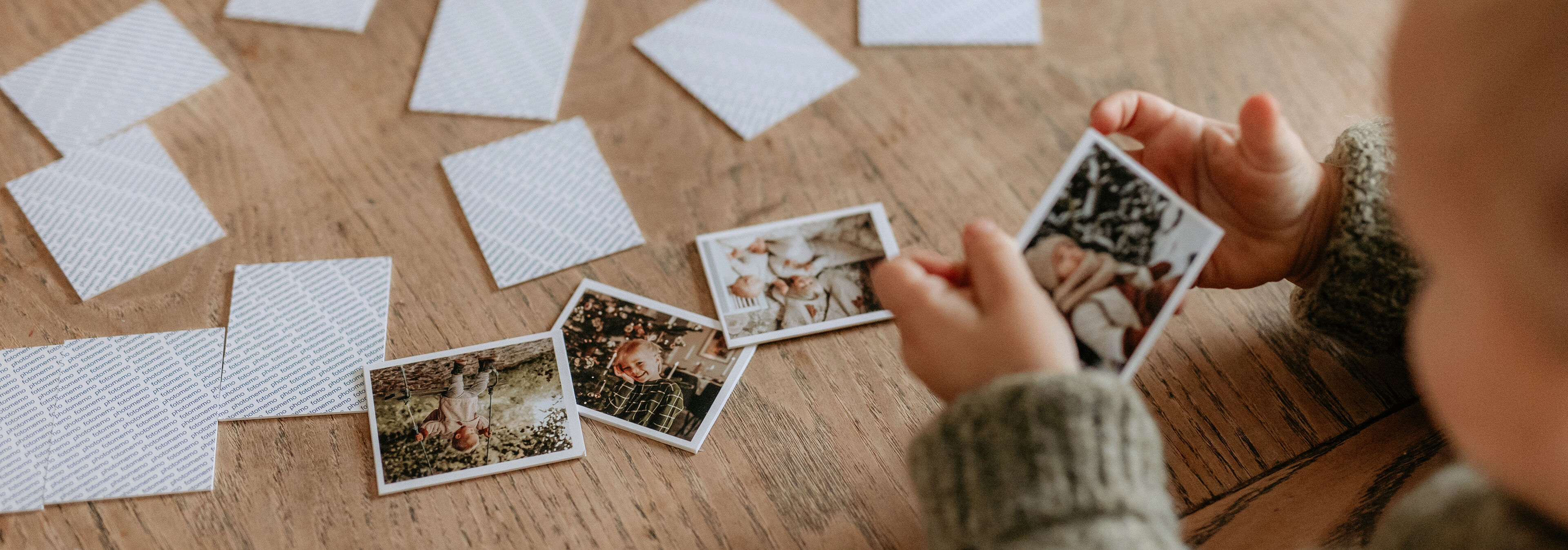 Ein Kleinkind, das sich mit kleinen Fotos von glücklichen Momenten beschäftigt. Die Fotos zeigen wunderschöne Erinnerungen.