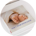 Ein offenes CEWE FOTOBUCH mit einem Bild von Babyfüßen und dem Titel „Unser Jahr mit Louis“