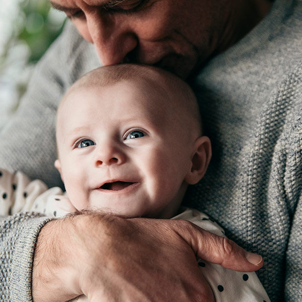 Vater hält sein Kind liebevoll im Arm und küsst es auf die Stirn