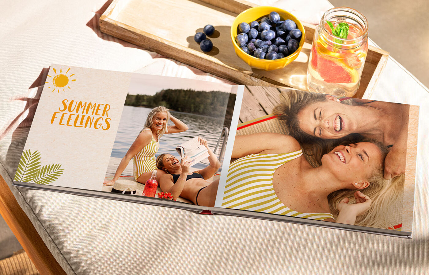 Zwei Frauen genießen den Sommer am Wasser mit einer Fruchtsmoothie und frischen Blaubeeren.