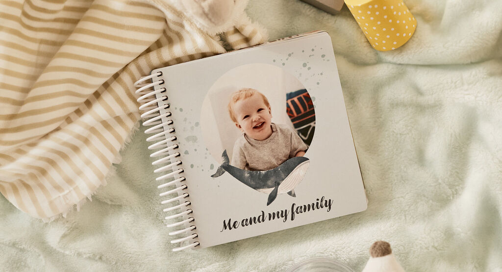 Ein CEWE FOTOBUCH mit dem Titel 'Me and my family' , liebevoll gestaltet mit einem Walmotiv. Es liegt auf einem weichen Untergrund.