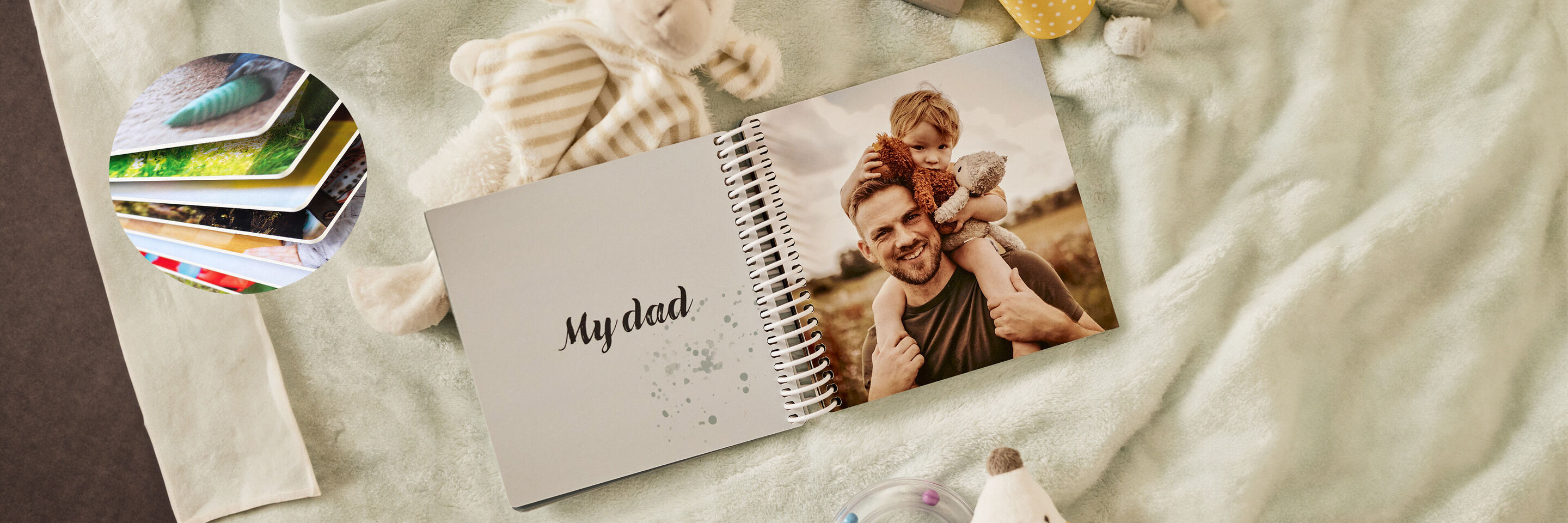 Ein offenes CEWE FOTOBUCH mit der Aufschrift 'My dad', umgeben von Spielzeug und einem sanften Hintergrund