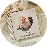 Ein CEWE FOTOBUCH mit einem lächelnden Baby auf dem Cover, umgeben von einem dekorativen Rahmen.