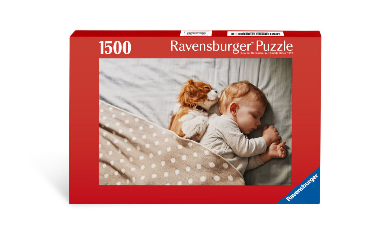 Ein neugieriges Kätzchen kuschelt sich an ein schlafendes Kind, während es auf einer gemütlichen Decke liegt