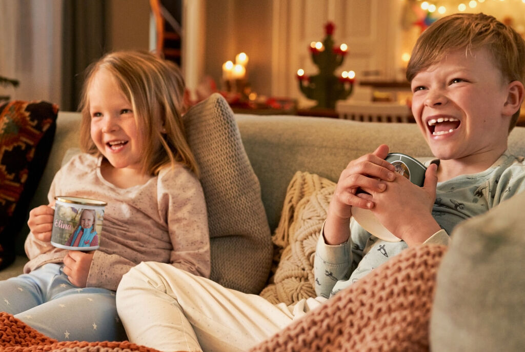 Kinder genießen warme Getränke auf dem Sofa, umgeben von festlicher Dekoration