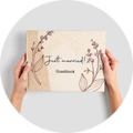 Une main tient un livre d'or décoré avec le titre 'Just married!'