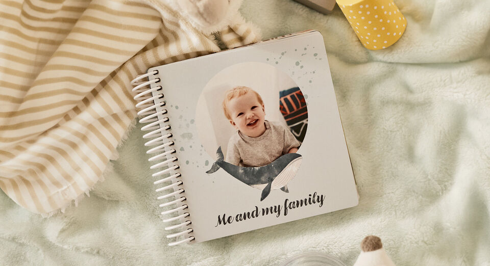 Un album CEWE intitulé 'Me and my family', décoré avec un motif de baleine, posé sur un fond doux.