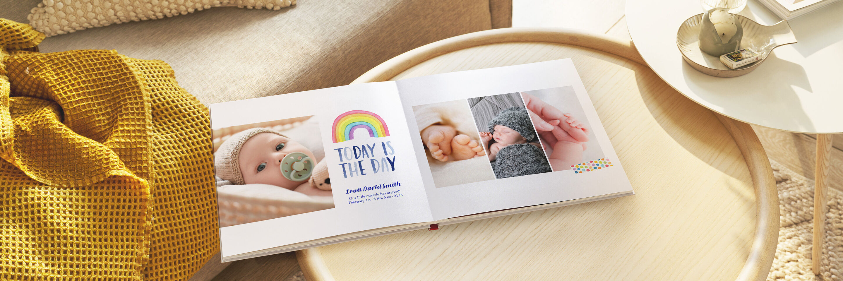 Un album photo ouvert sur une table avec des photos de bébés et un arc-en-ciel coloré. Une couverture douce à côté.