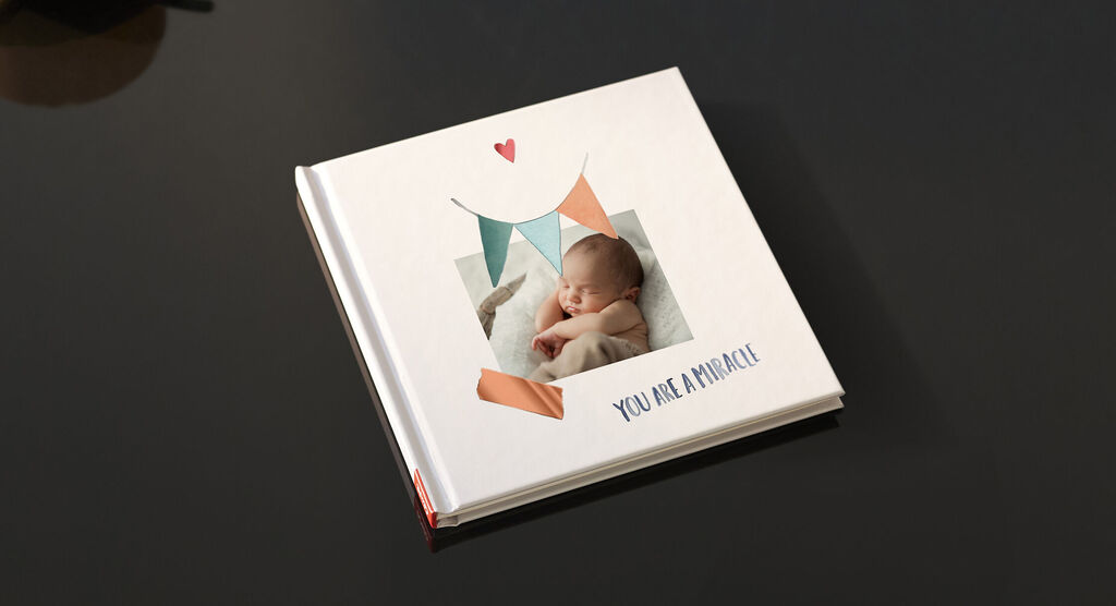 Un album photo CEWE magnifiquement conçu avec une photo d'un bébé dormant sur la couverture.