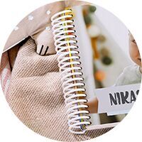 Gros plan d’un carnet ouvert à spirale, à côté d’une photo d’un jeune enfant nommé Nika.
