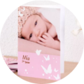 Un adorable livre photo CEWE montre un bébé avec un joli bandeau. Le nom Mia figure sur la couverture.